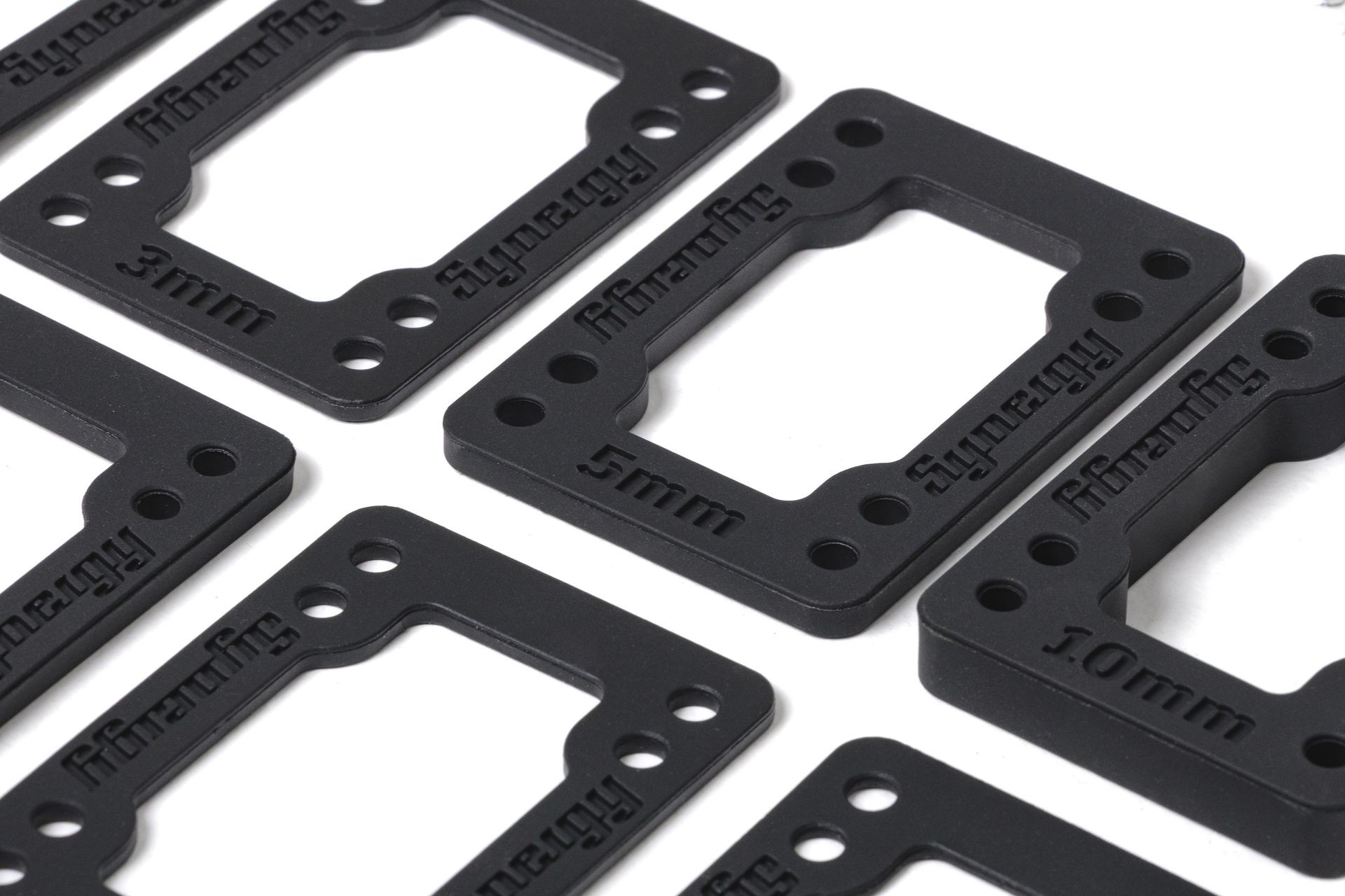 Close-up of black rectangular spacer plates with various thickness measurements embossed on them.